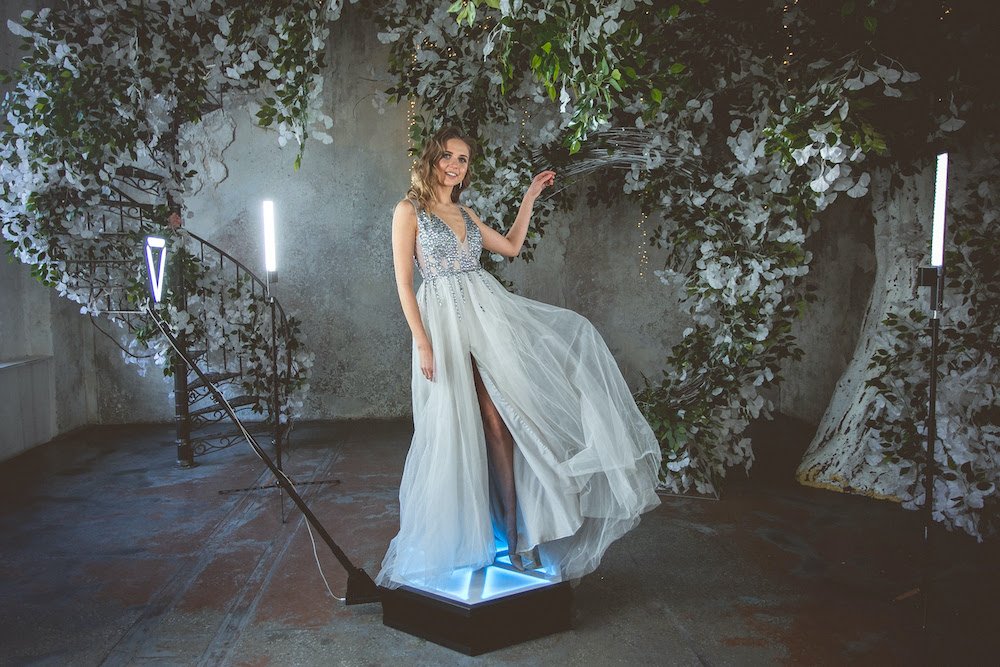 Woman in a glamorous gown posing on a rotating 360 photo booth platform.